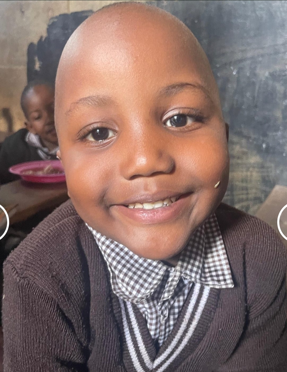 A student in school uniform smiling after lunch at the center
